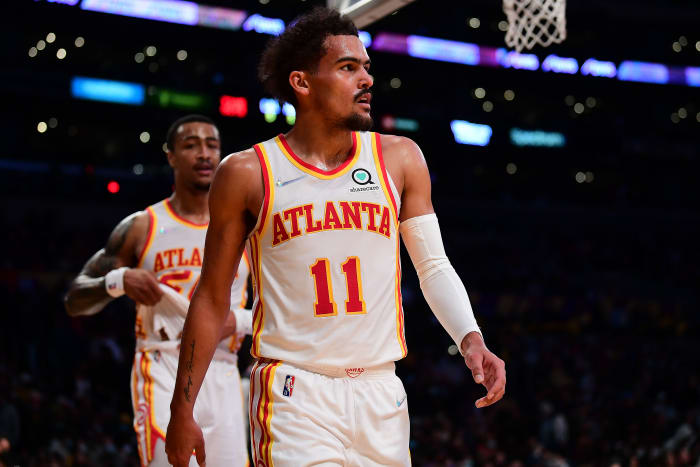 Trae Young and John Collins walk towards the bench.
